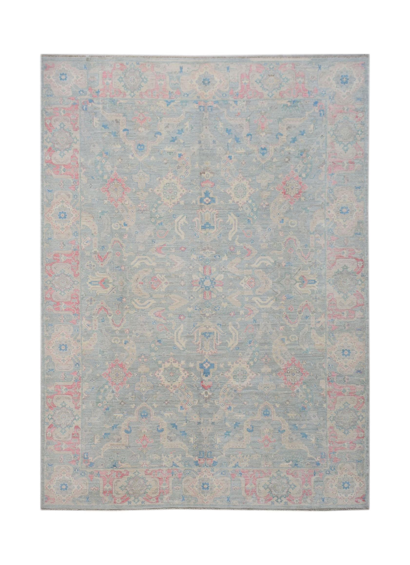 A handwoven transitional Oushak rug featuring a floral pattern in soft blue and pink tones.