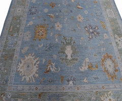 Handmade Afghan Oushak rug featuring a traditional floral pattern in shades of blue and tan.