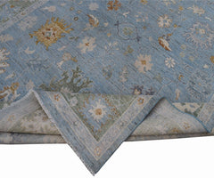 A handmade Afghan Oushak rug featuring a traditional floral pattern in shades of blue and cream.