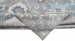 A handwoven transitional Oushak rug featuring a floral pattern in shades of blue, grey, and beige.
