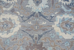 A handwoven transitional Oushak rug featuring a floral pattern in shades of blue, grey, and cream.