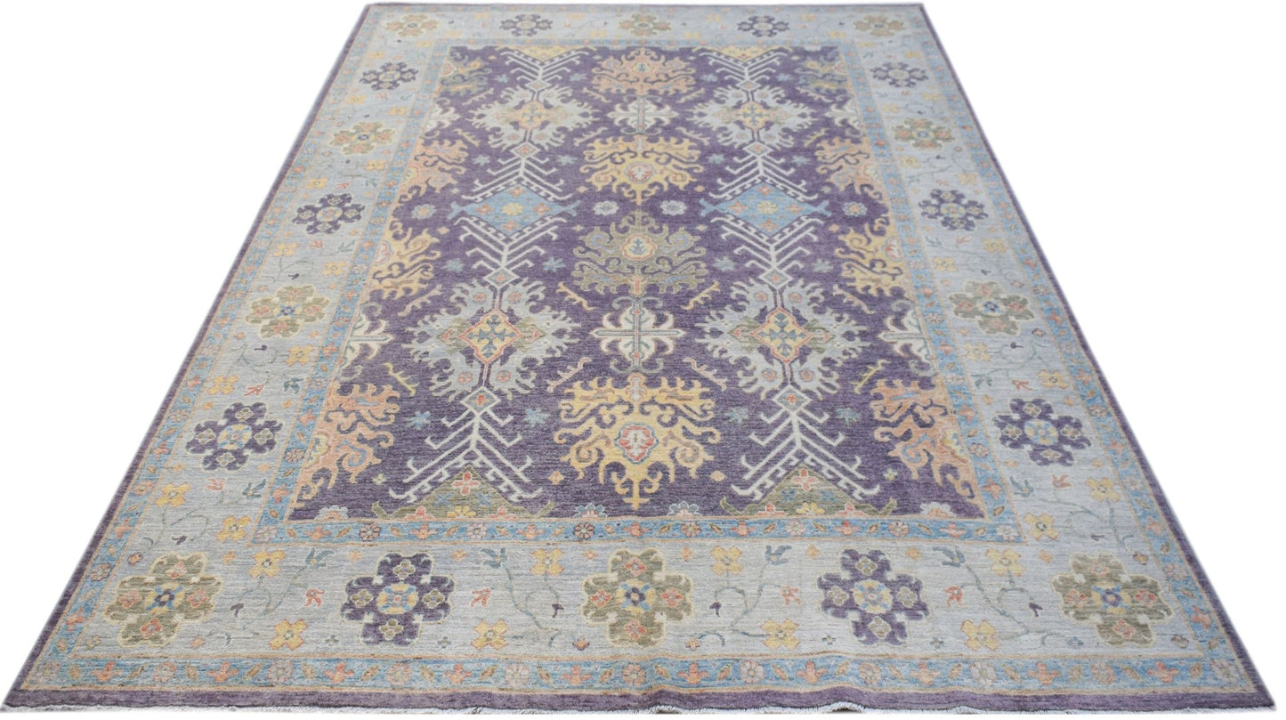 A handwoven transitional Oushak rug featuring a floral pattern in purple, blue, and yellow tones.