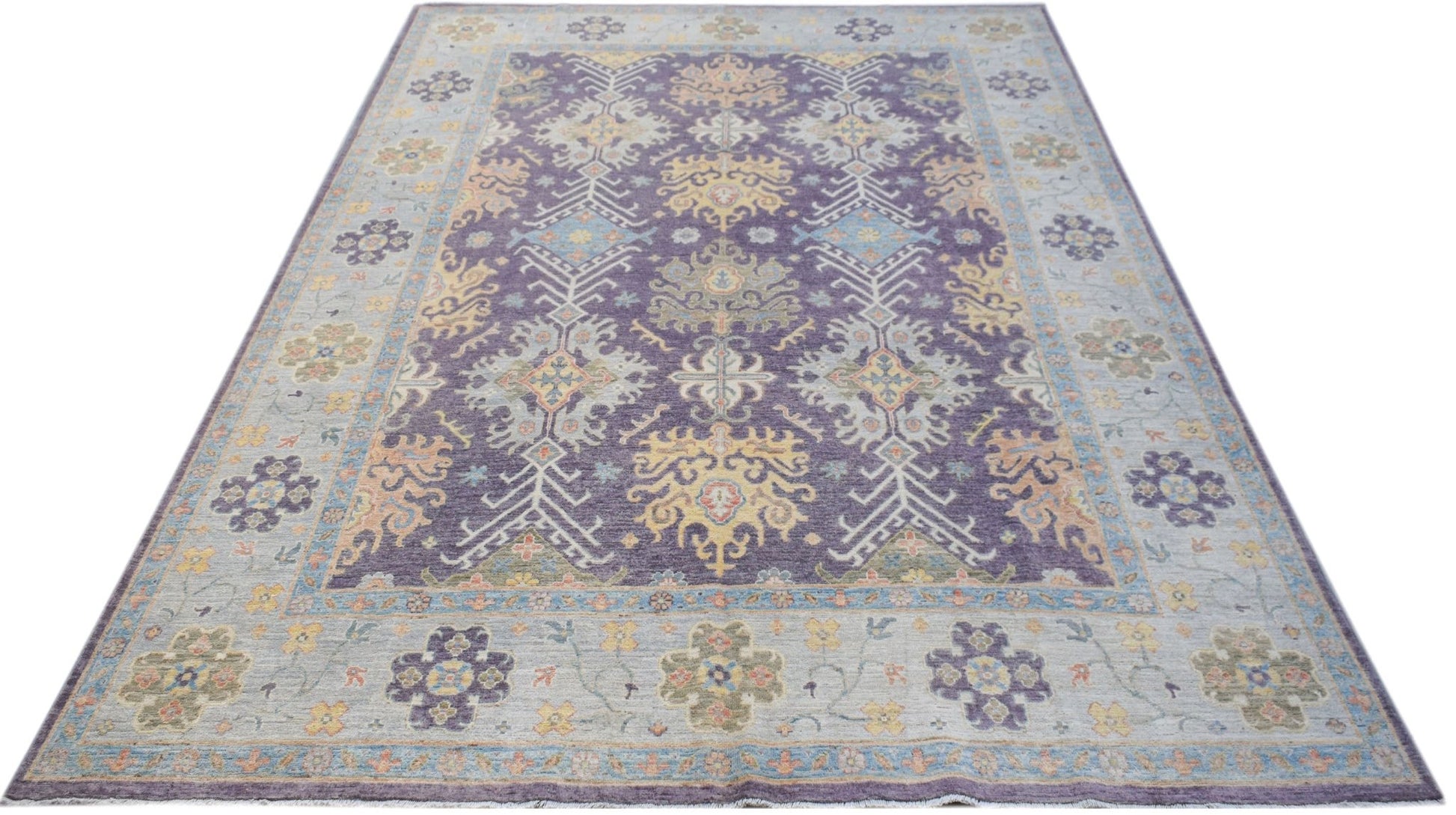 A handwoven transitional Oushak rug featuring a floral pattern in purple, blue, and yellow tones.
