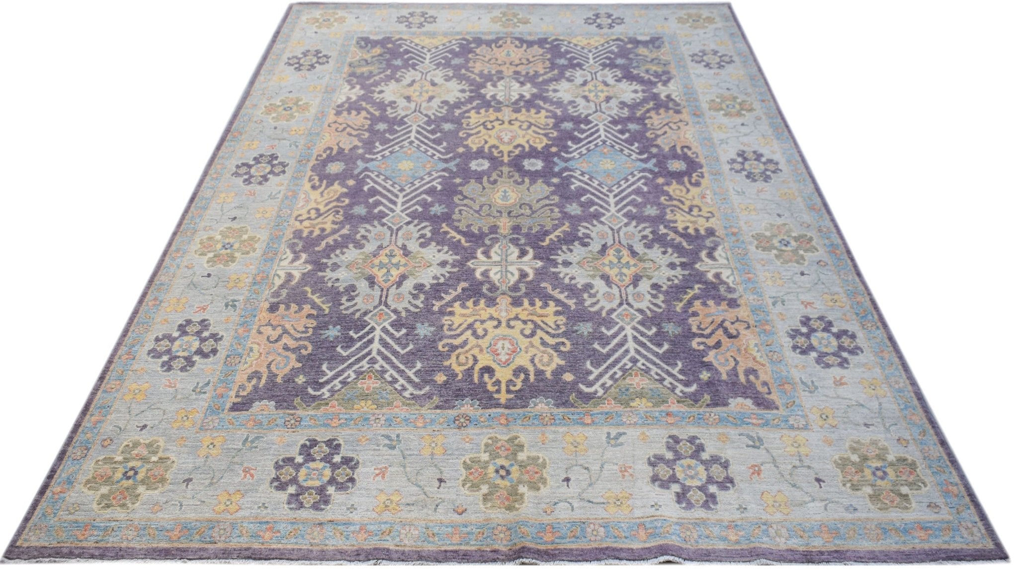 A handwoven transitional Oushak rug featuring a floral pattern in purple, blue, and yellow tones.