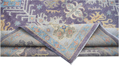 A handwoven transitional Oushak rug featuring a floral pattern in purple, blue, and yellow tones.