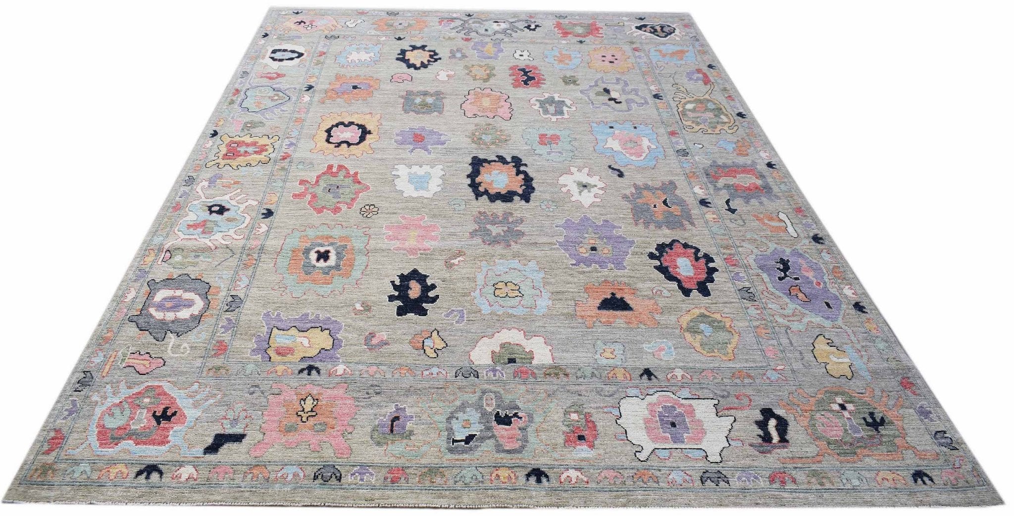 A handwoven transitional Oushak rug featuring a grey field with colorful floral motifs.