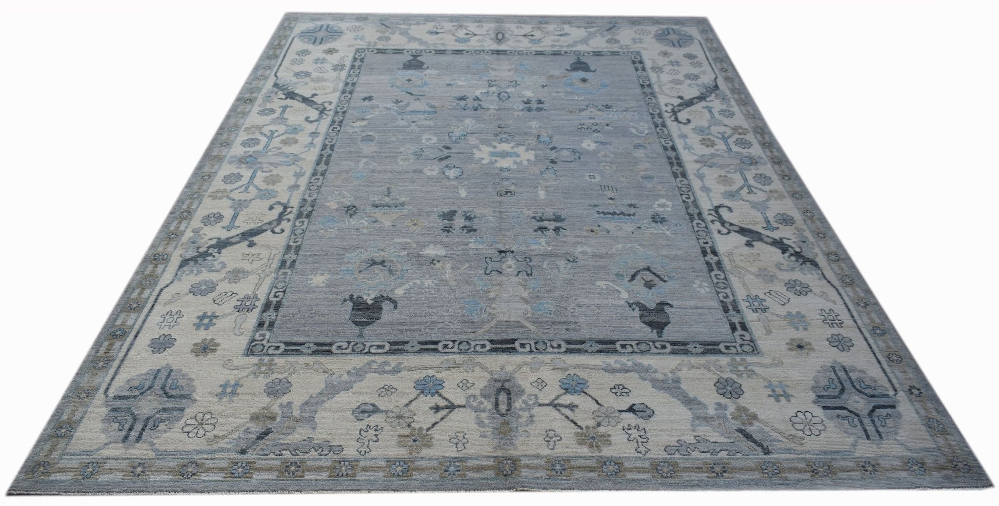 A handwoven transitional Oushak rug featuring a floral pattern in shades of blue and grey.