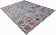 A handwoven transitional Oushak rug featuring a light grey field with colorful floral motifs.