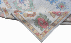 A handwoven transitional Oushak rug featuring a light blue field with colorful floral motifs.