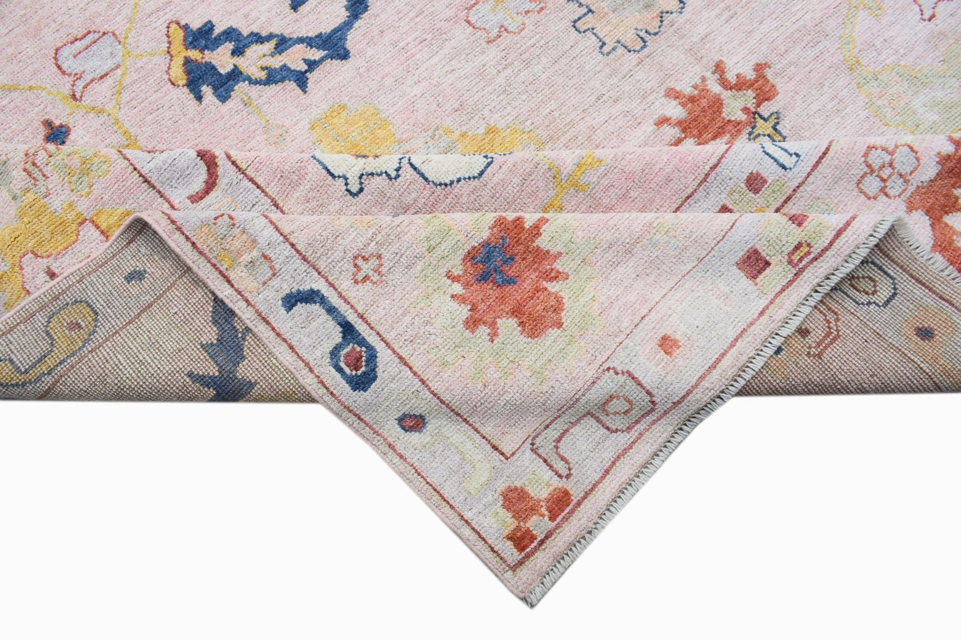 A handwoven transitional Oushak rug featuring a floral pattern in soft pink, blue, and orange tones.
