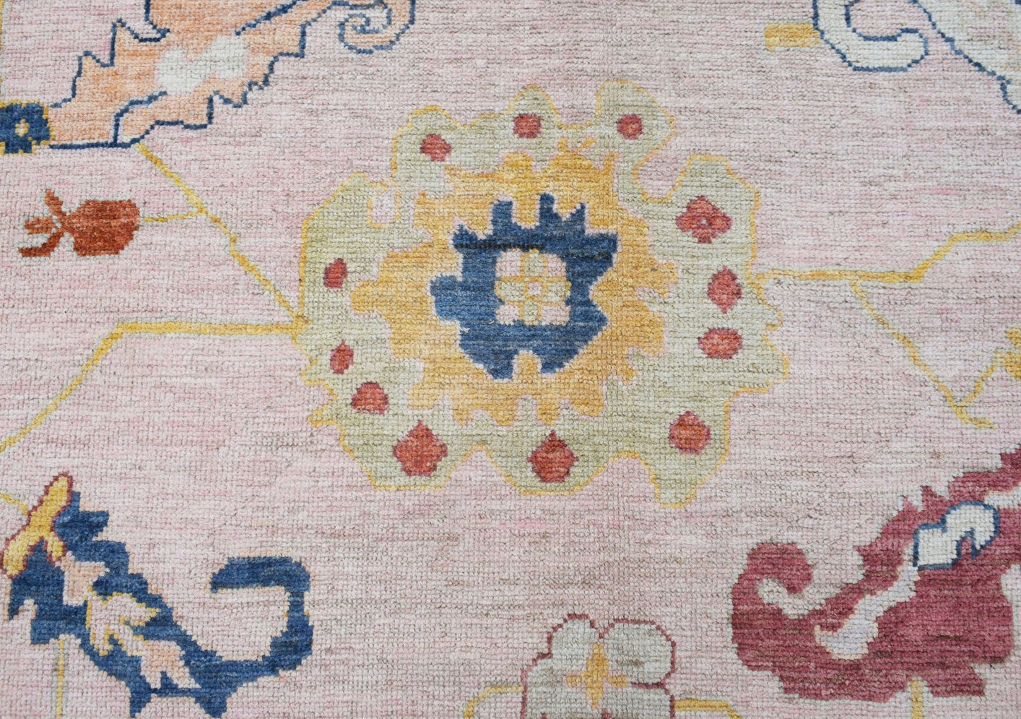 A transitional Oushak rug featuring a floral pattern in soft pink, blue, yellow, and red tones.