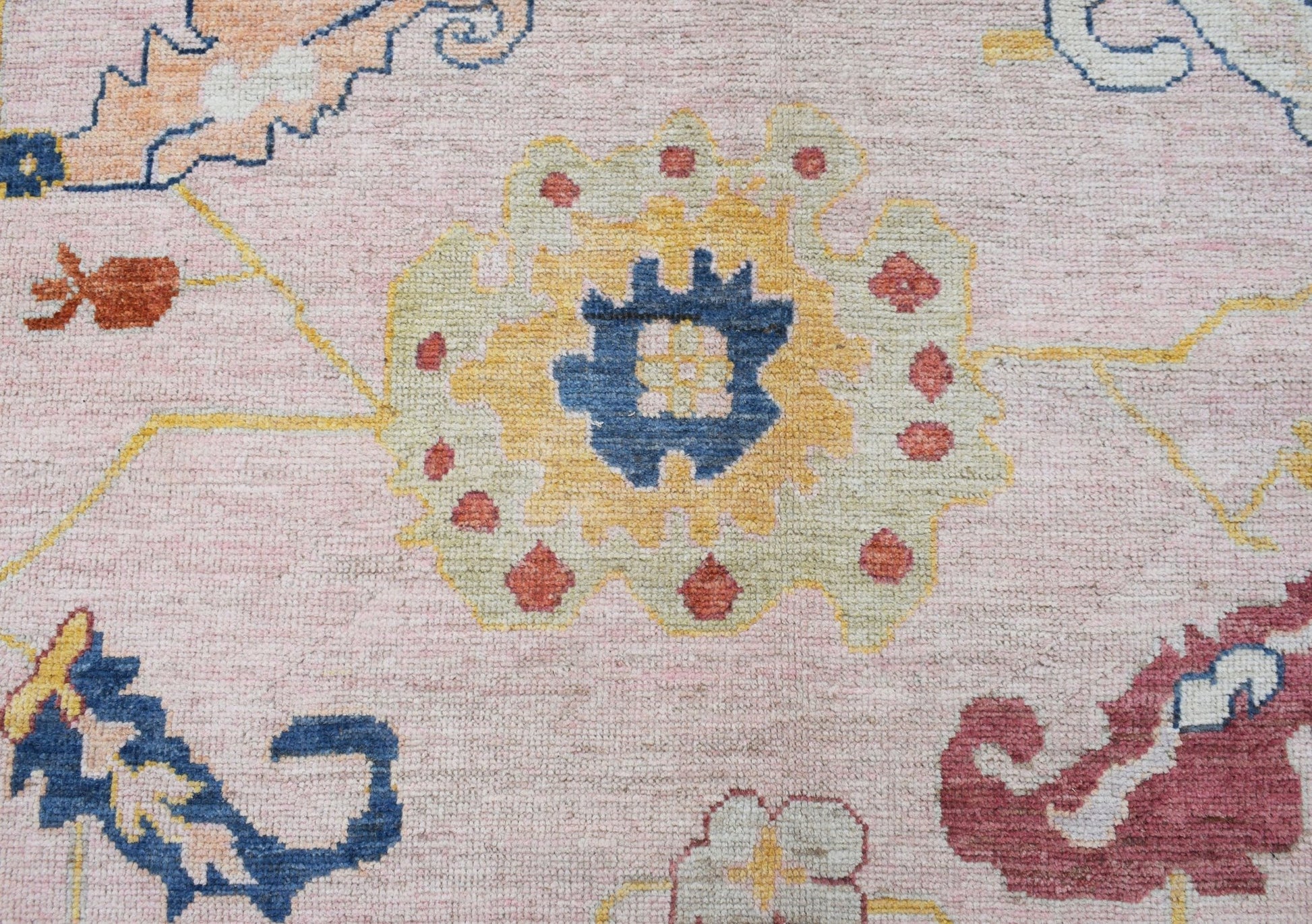 A transitional Oushak rug featuring a floral pattern in soft pink, blue, yellow, and red tones.