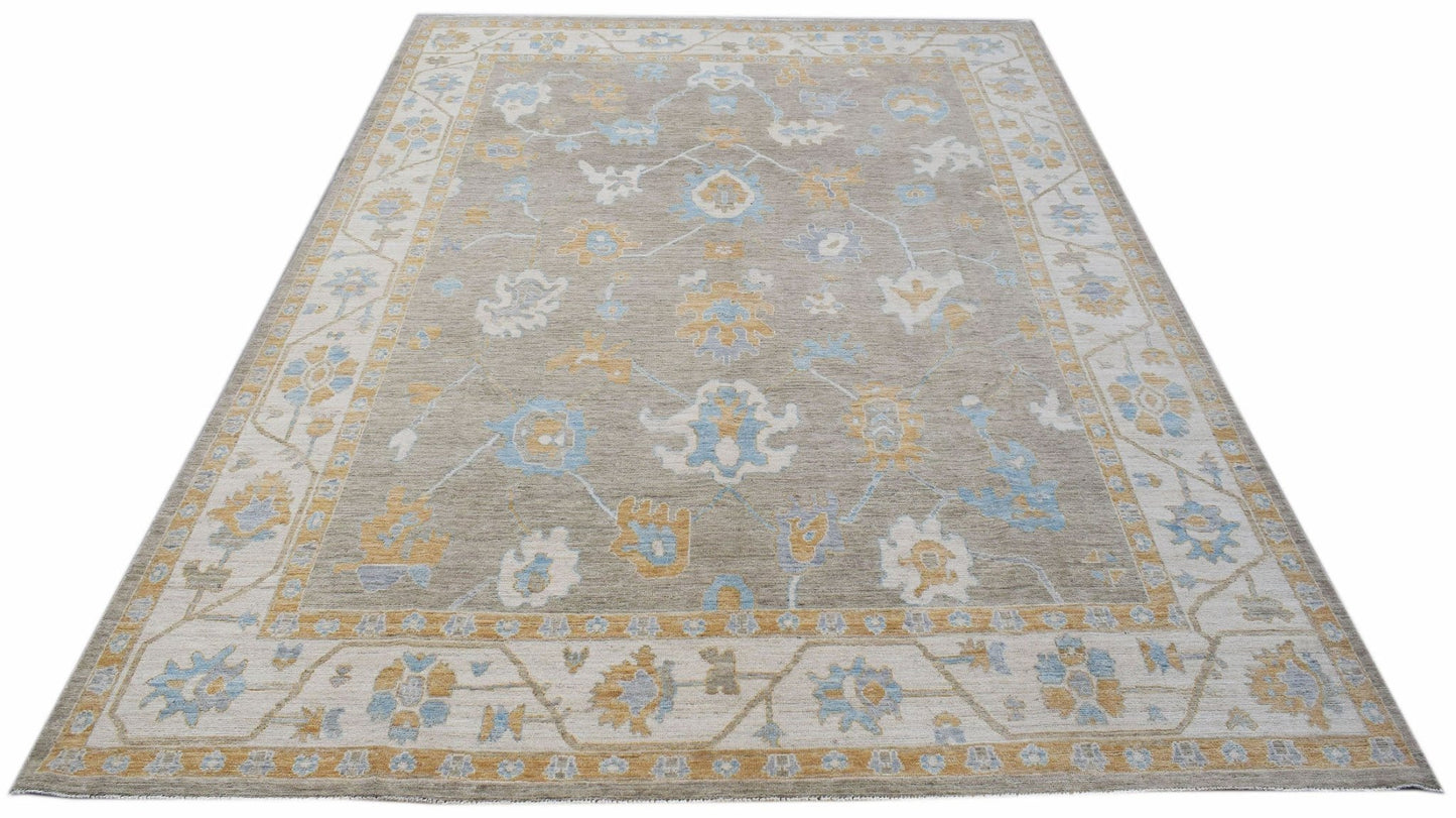 A handwoven transitional Oushak rug featuring a floral pattern in blue and gold on a grey field.
