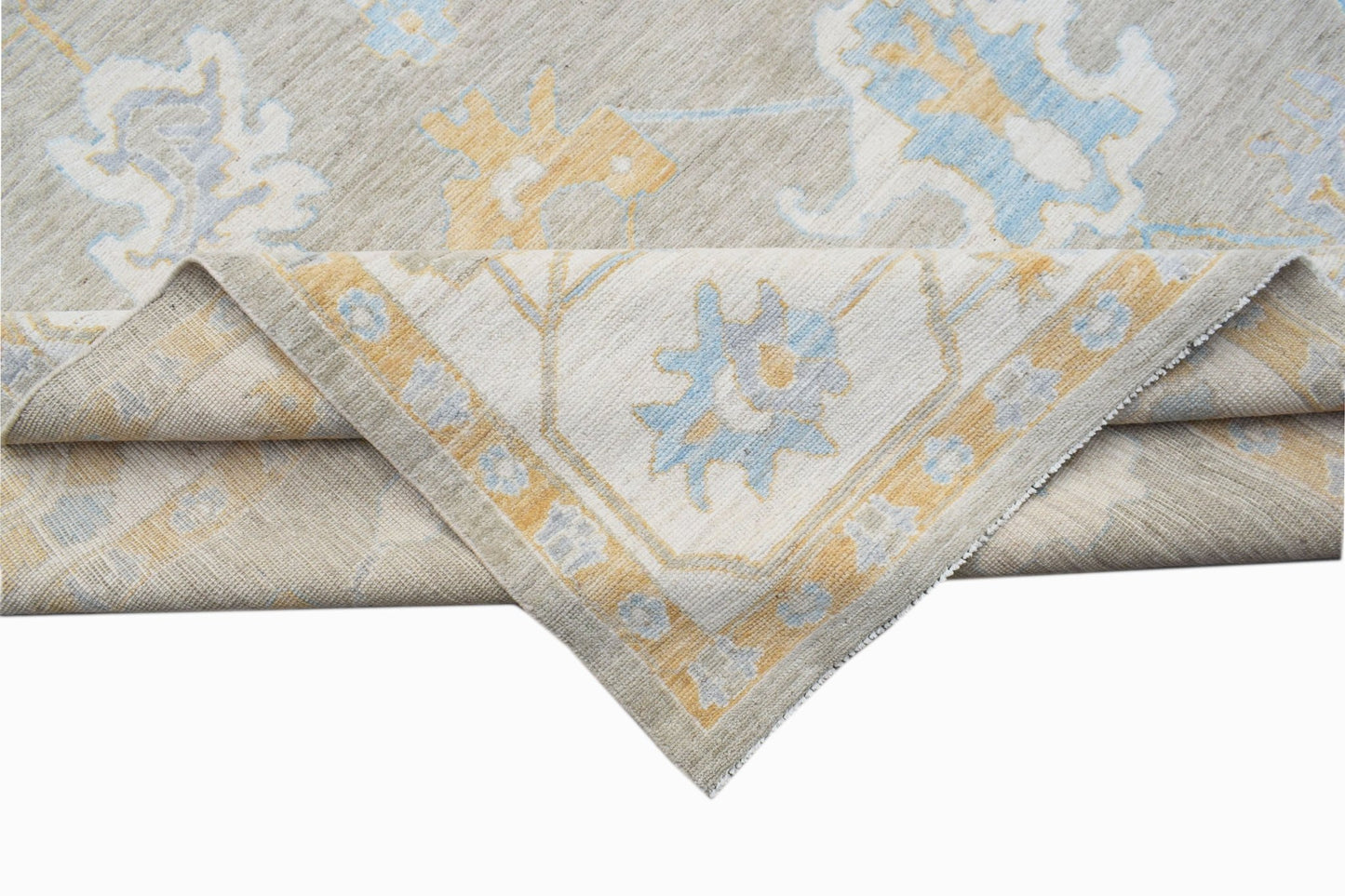A handwoven transitional Oushak rug featuring a floral pattern in soft blue and yellow tones.