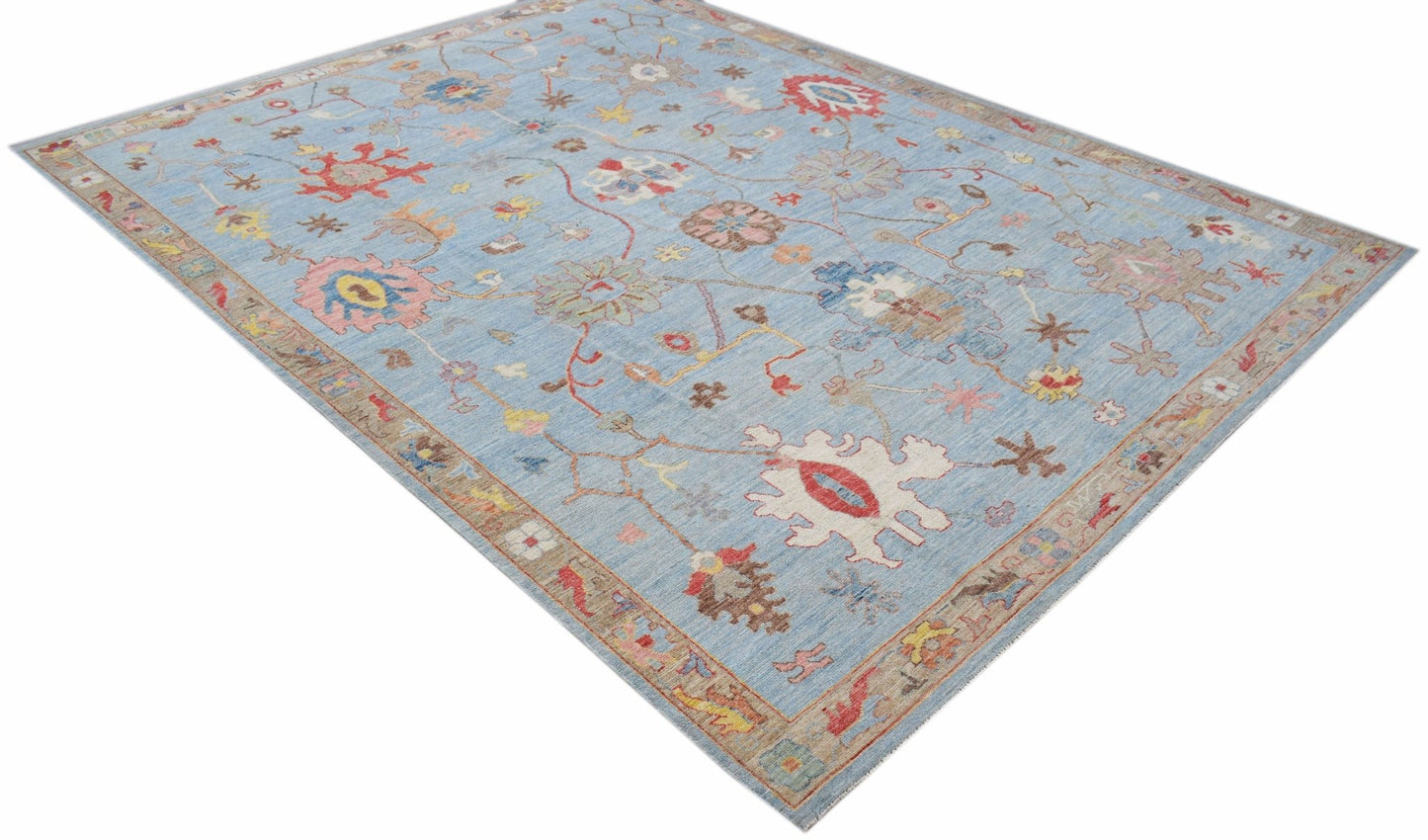 A handwoven transitional Oushak rug featuring a floral pattern on a light blue background.