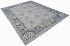 A handwoven transitional Oushak rug featuring a floral pattern in blue, grey, and yellow tones.