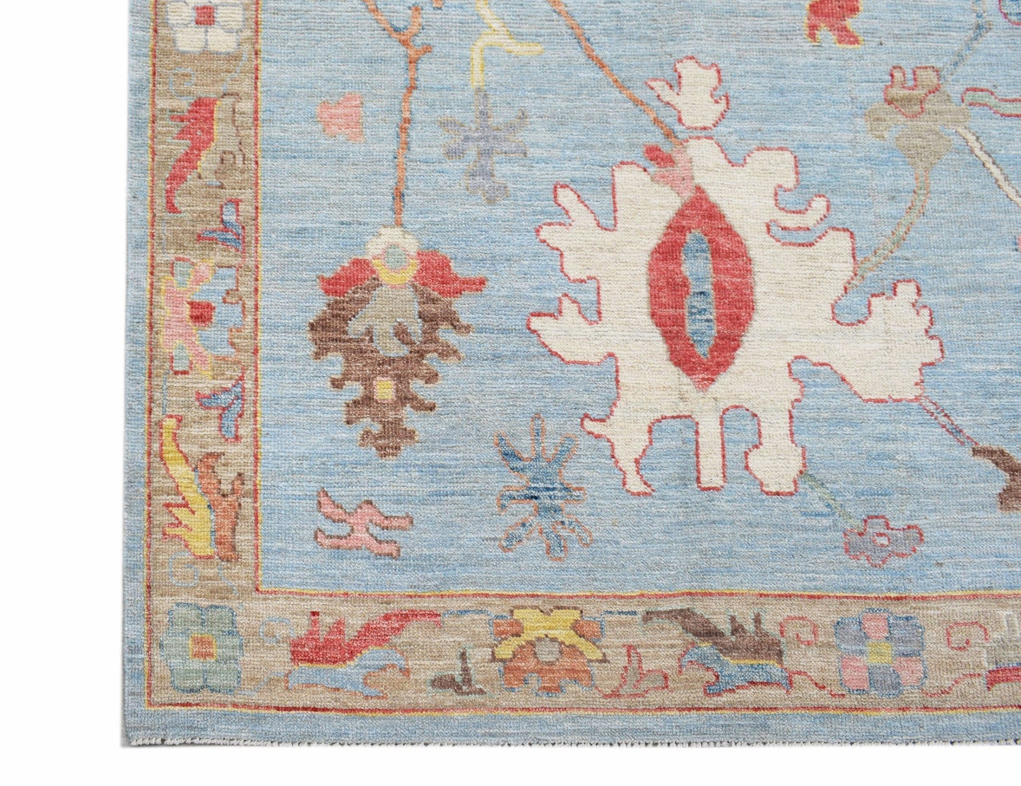 A handwoven transitional Oushak rug featuring a light blue field with floral motifs and a tan border.