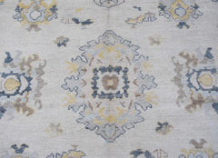 A handwoven transitional Oushak rug featuring a floral pattern in soft blue, yellow, and grey.