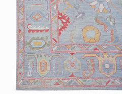 A handwoven transitional Oushak rug featuring a light blue field with colorful floral motifs.