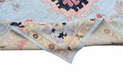 A handwoven transitional Oushak rug with a light blue field and floral patterns in muted tones.