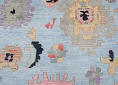 A handwoven wool rug featuring a light blue background with abstract, colorful floral motifs.
