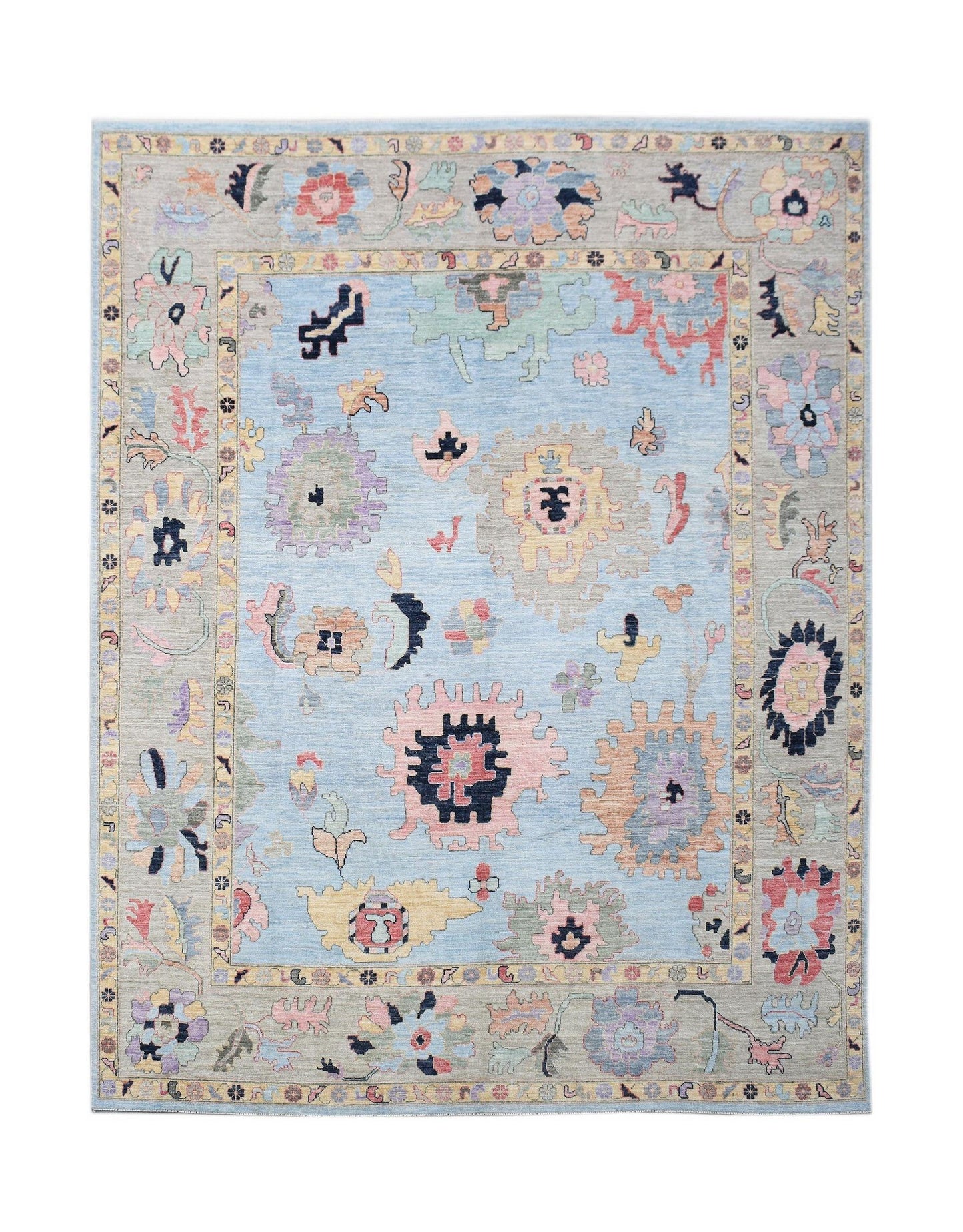 A handwoven transitional Oushak rug featuring a light blue field with colorful floral motifs.