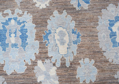 A transitional Oushak rug featuring a blue and cream floral pattern on a textured brown background.