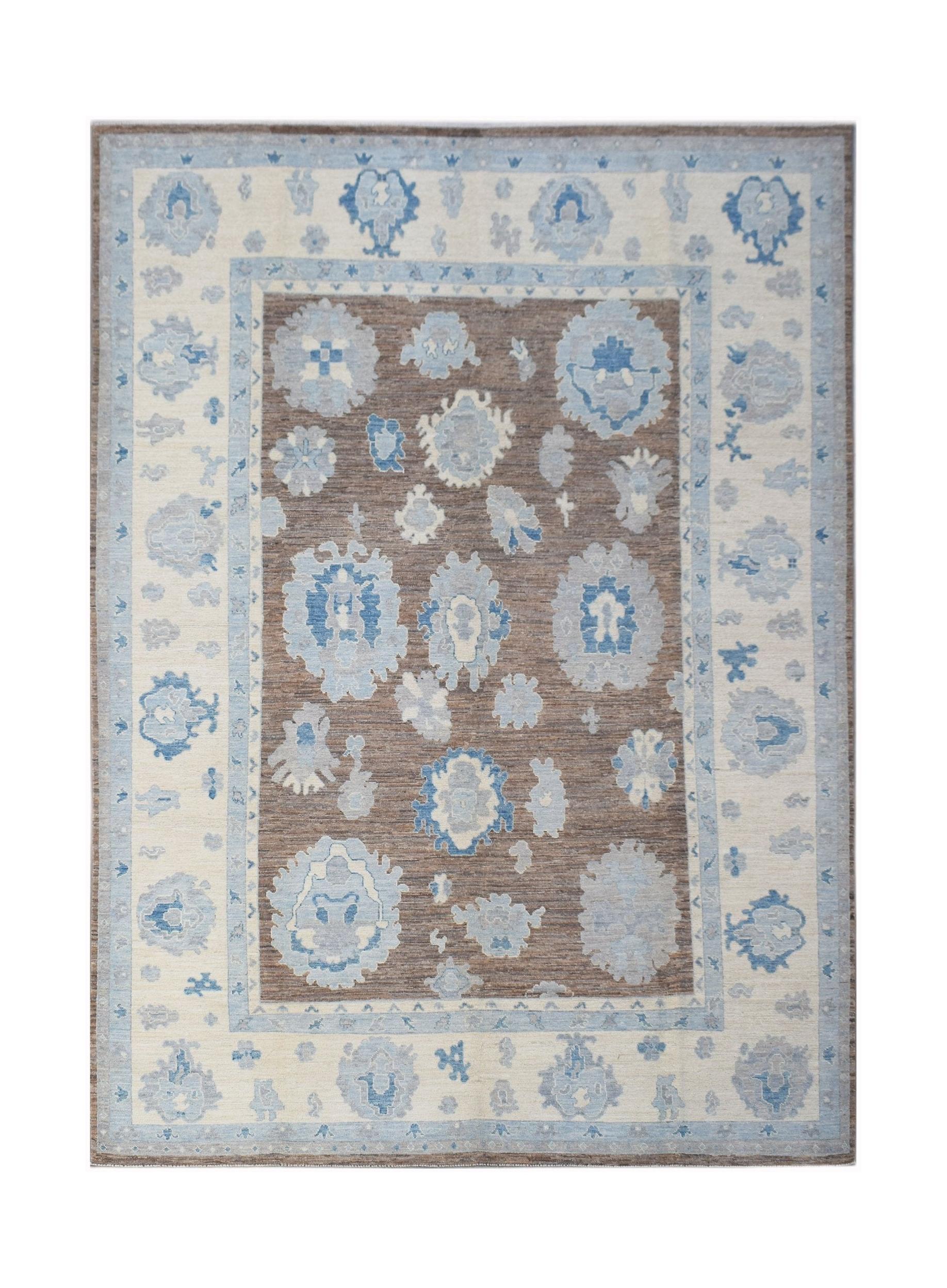 A handwoven transitional Oushak rug featuring blue floral motifs on a brown field and cream border.