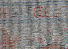 A close-up of a handwoven wool rug featuring a transitional pattern in soft, muted tones.