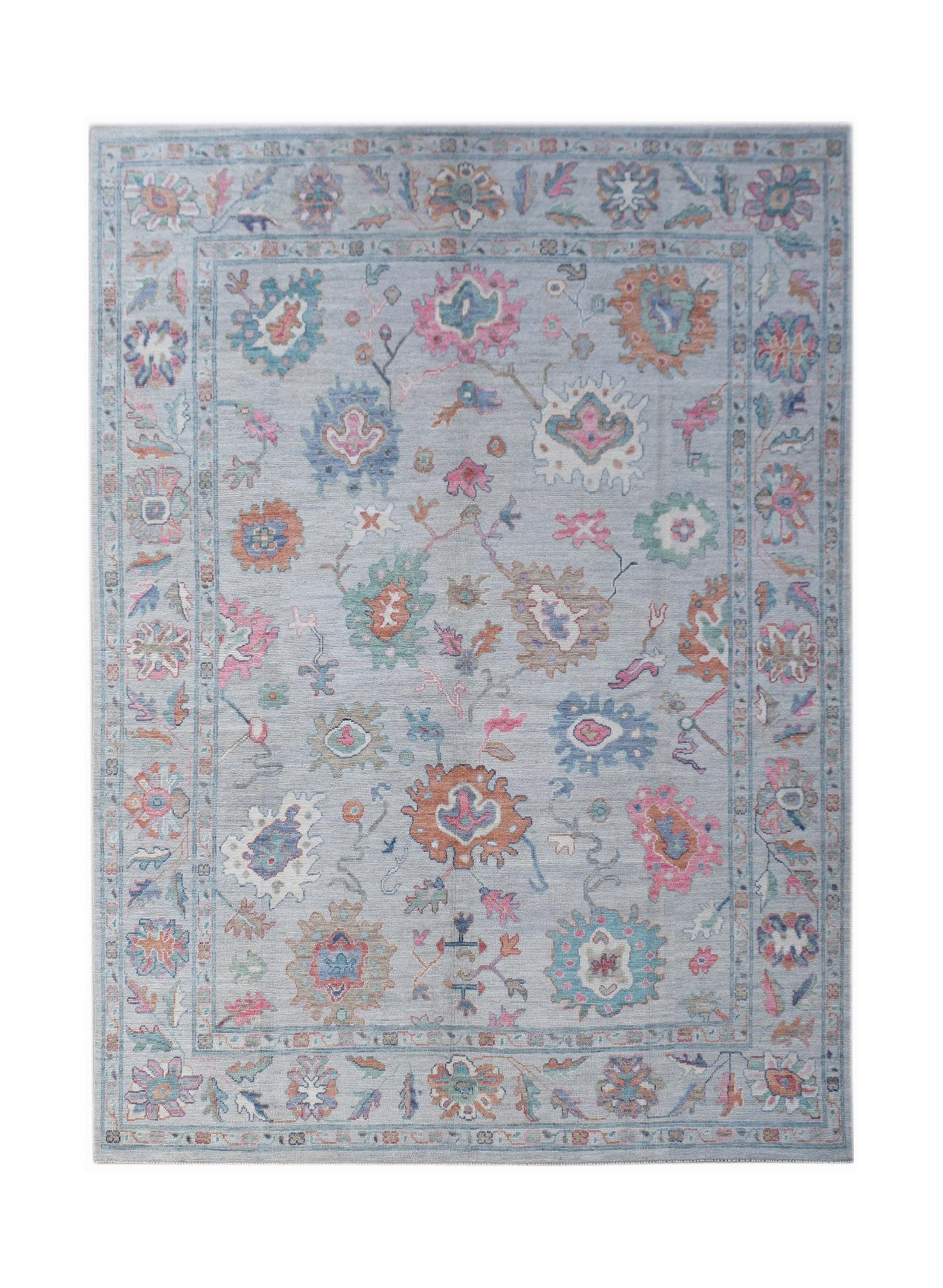 A handwoven transitional Oushak rug featuring a floral pattern in soft colors on a light blue base.