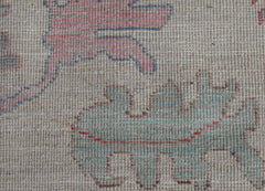 A close-up view of a handwoven wool rug featuring stylized pomegranate motifs in soft tones.