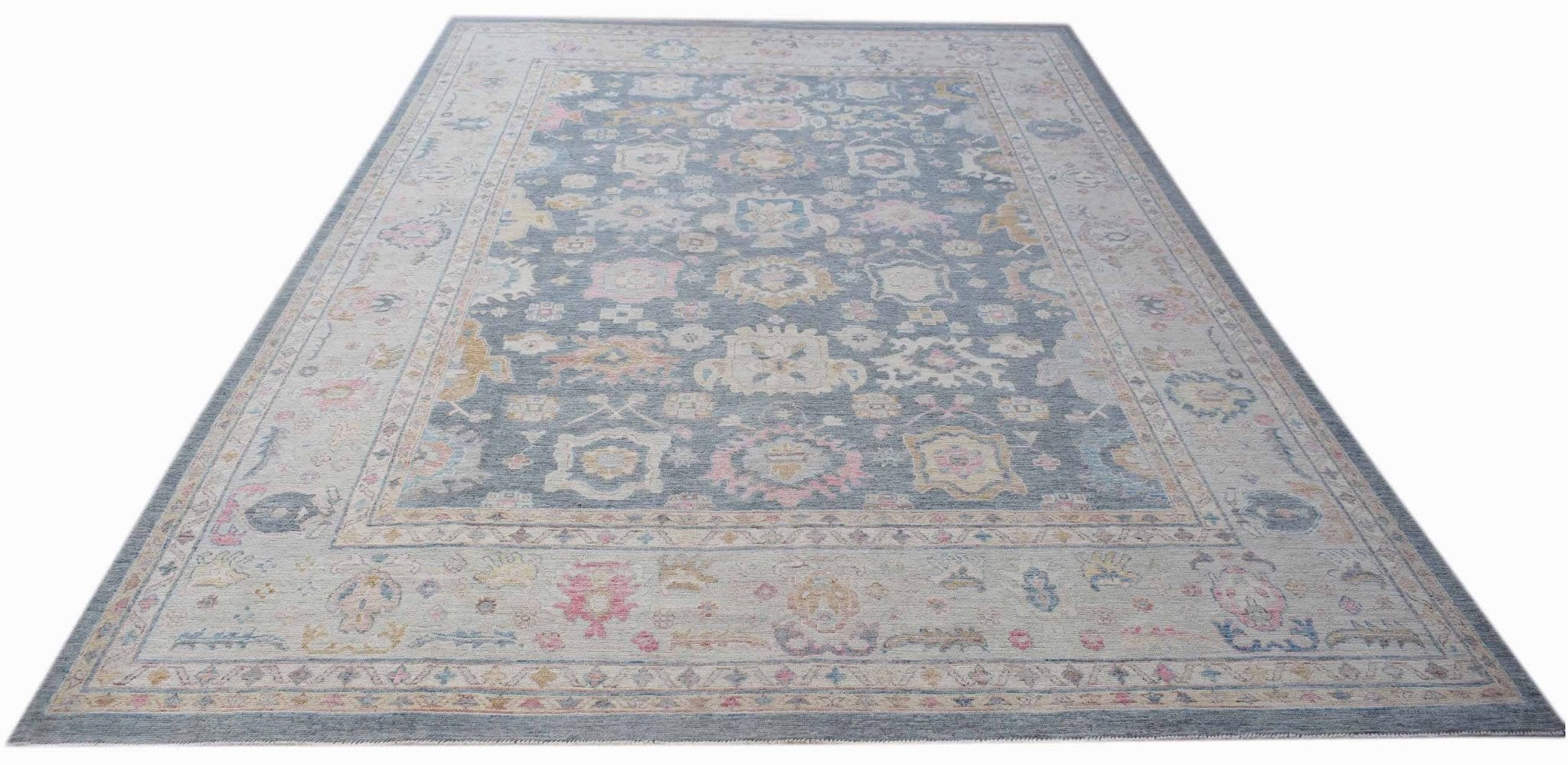 A handwoven transitional Oushak rug featuring a floral pattern in blue, pink, and cream tones.