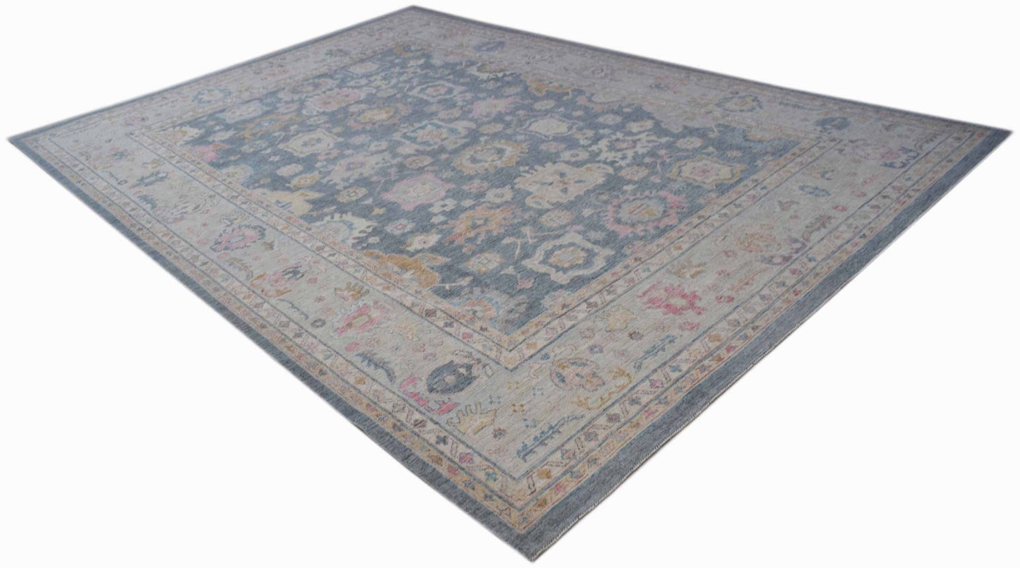 A handwoven transitional Oushak rug featuring a floral pattern in blue, pink, and cream tones.