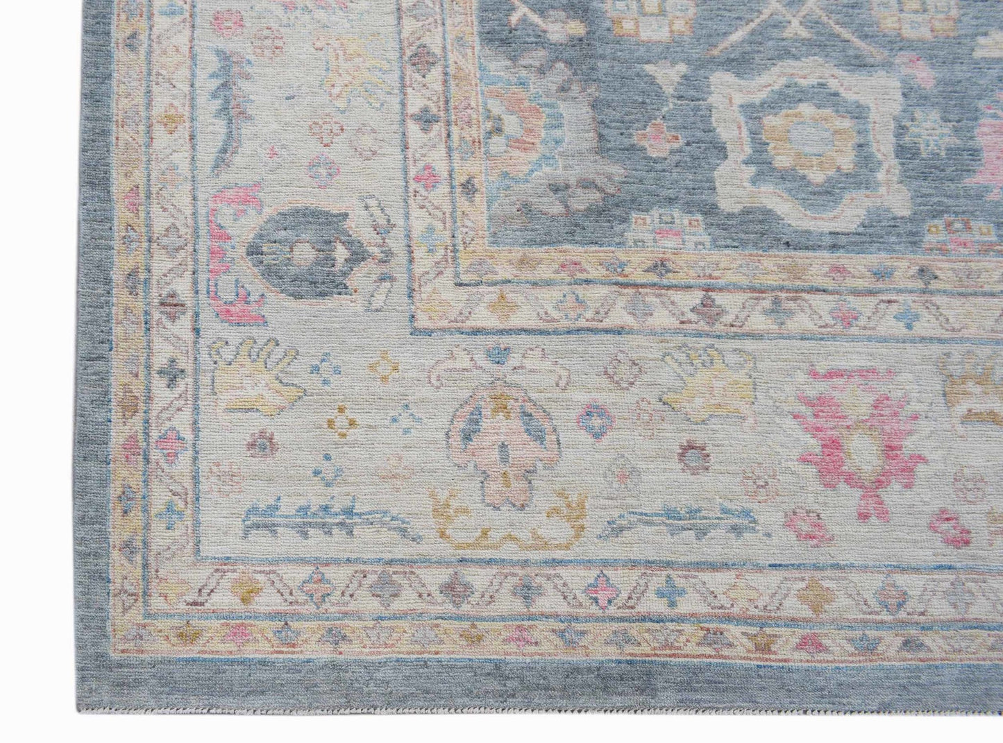A handwoven transitional Oushak rug featuring a floral pattern in soft blue, pink, and cream tones.