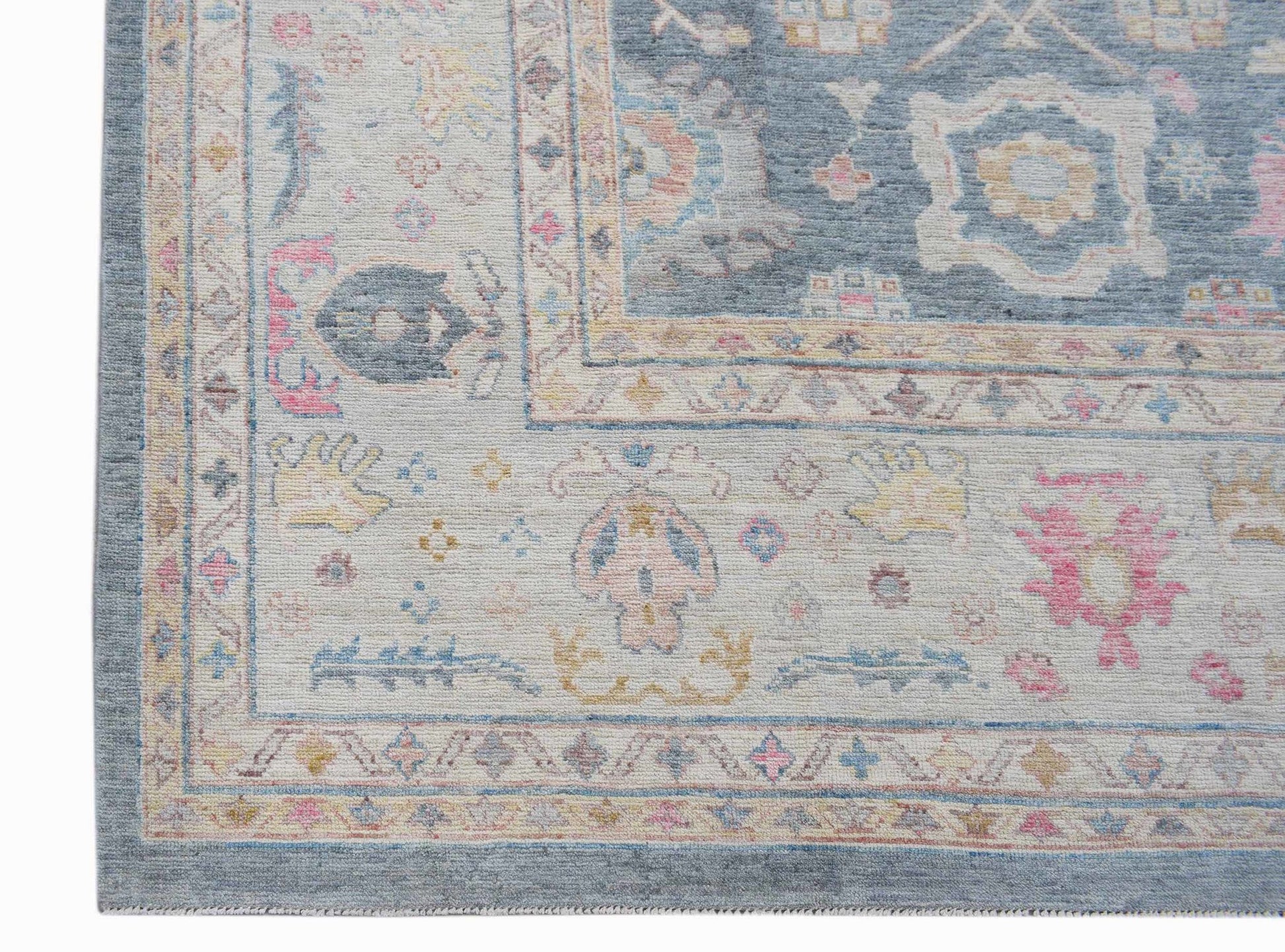 A handwoven transitional Oushak rug featuring a floral pattern in soft blue, pink, and cream tones.