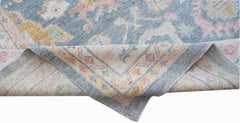 A handwoven transitional Oushak rug in blue with floral patterns in pink and yellow tones.