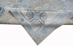 A handwoven transitional Oushak rug featuring a light beige and blue floral pattern.
