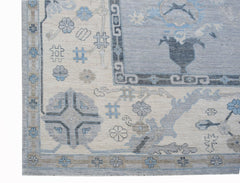 A transitional Oushak rug featuring a blue and cream floral pattern with a geometric border.