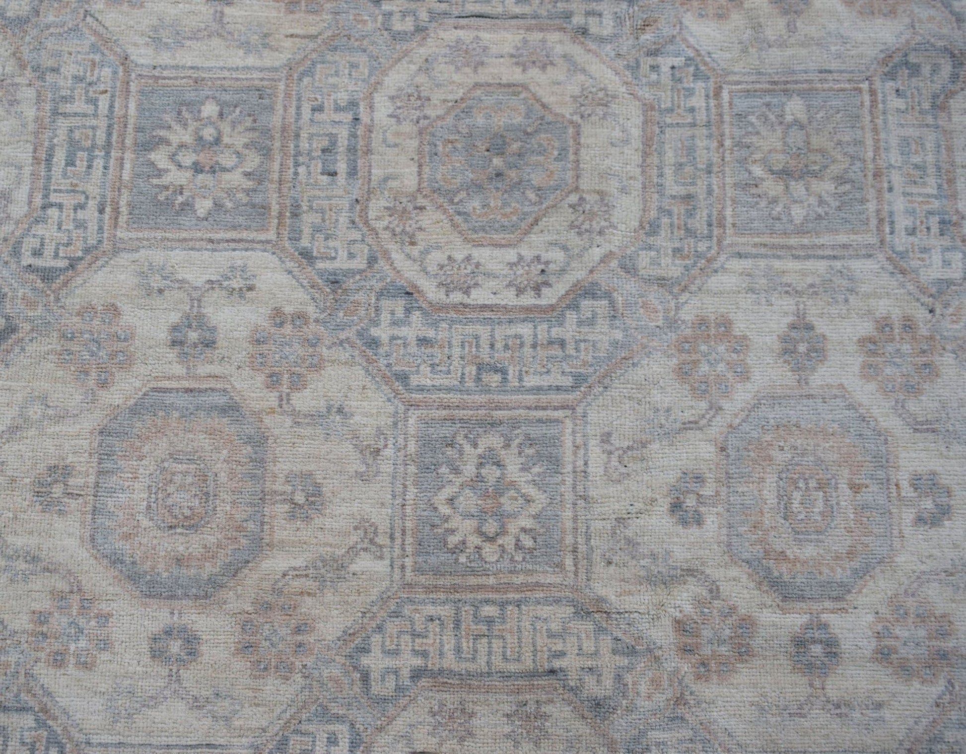 A handwoven transitional Oushak rug featuring a geometric floral pattern in soft neutral tones.