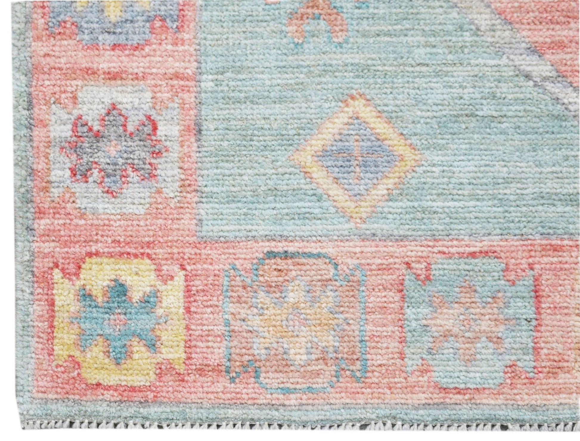 A handwoven wool runner featuring a transitional Oushak pattern in soft blue and pink tones.