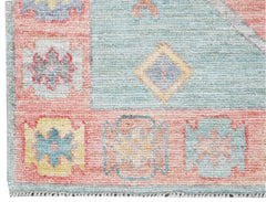 A handwoven wool runner featuring a transitional Oushak pattern in soft blue and pink tones.