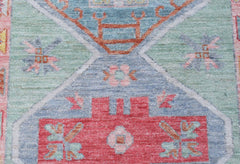 A handwoven wool runner featuring a transitional Oushak pattern in blue, green, and red tones.