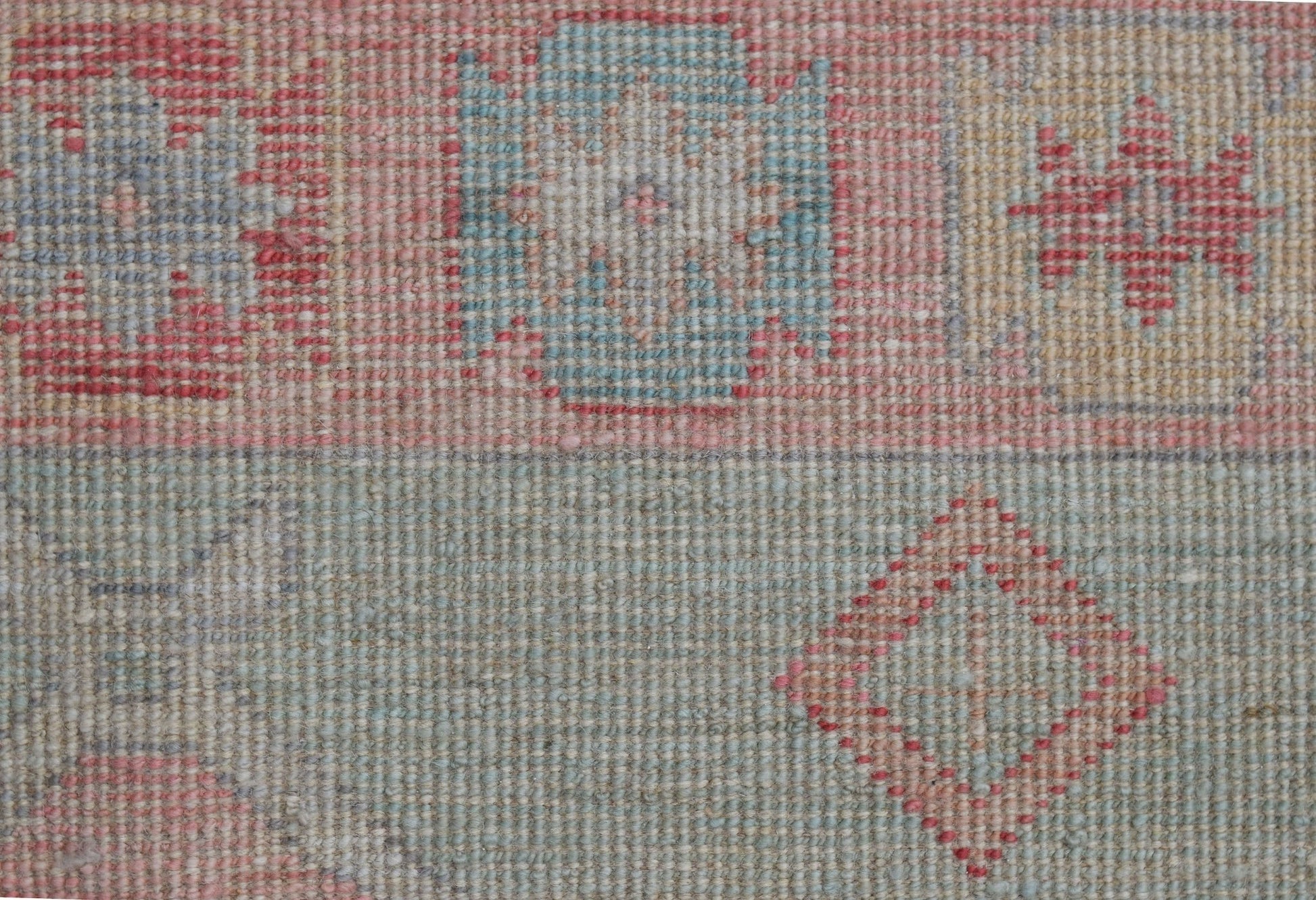 A handwoven wool runner featuring a transitional Oushak pattern in soft blue and red tones.