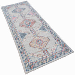 A handwoven wool runner rug featuring a transitional Oushak pattern in blue, pink, and cream tones.