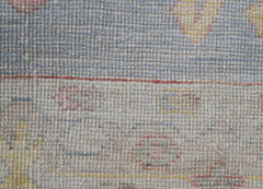 A close-up of a handwoven wool runner featuring a transitional floral pattern in muted tones.