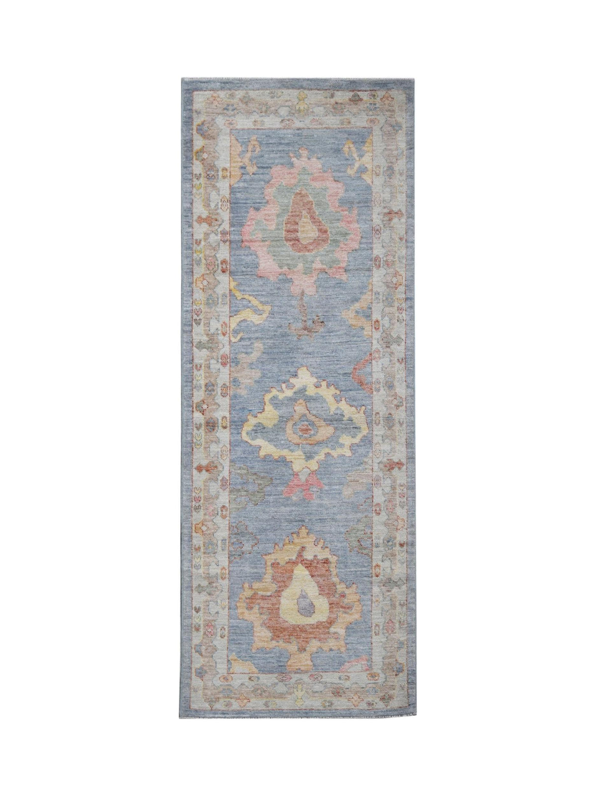 A handwoven wool runner rug featuring a blue field with traditional floral motifs in soft colors.