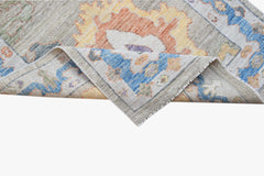 A handwoven transitional Oushak runner featuring a floral pattern in blue, orange, and yellow.