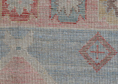 A close-up of a handwoven wool runner featuring a transitional pattern in soft blue and red tones.