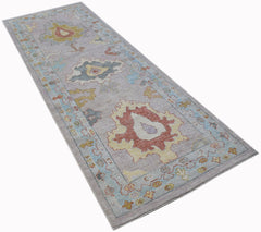 A handwoven wool runner rug featuring a transitional Oushak pattern in soft, muted tones.