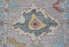 A handwoven wool runner featuring a transitional floral pattern in soft grey, yellow, and blue.
